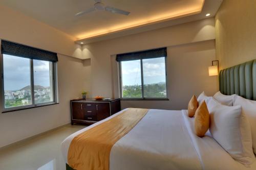 a bedroom with a large bed with two windows at The Fern Residency, Vadgaon - Talegaon, Pune in Pune
