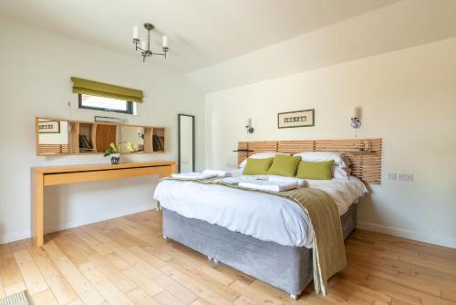 a bedroom with a large bed and a kitchen at Tor Farm Lodges - Private Hot Tubs, Shared Seasonal Outdoor Pool, Dog Friendly in Cheddar