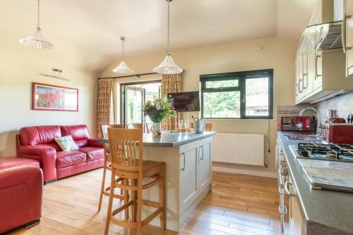 a kitchen with a red couch and a kitchen island at Tor Farm Lodges - Private Hot Tubs, Shared Seasonal Outdoor Pool, Dog Friendly in Cheddar