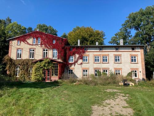 an old house with ivy on it in a field at Wohnen im Gutshaus in Lalendorf