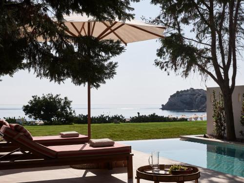 a person laying in a lounge chair next to a pool at Port Royal Villas and Spa - Adults Only in Kolimbia