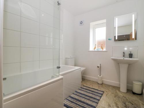 a white bathroom with a shower and a sink at The Bay in Benllech