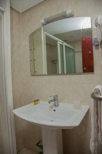 a white sink in a bathroom with a mirror at Hôtel La Rose Blanche Abidjan in Abidjan