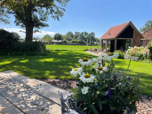 a bench with flowers in the middle of a yard at Domestico Bed & Breakfast in Lage Mierde