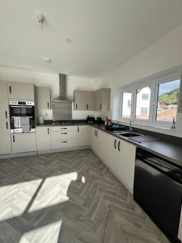 a kitchen with white cabinets and a black dishwasher at Beach side family rest and holiday in Llandudno