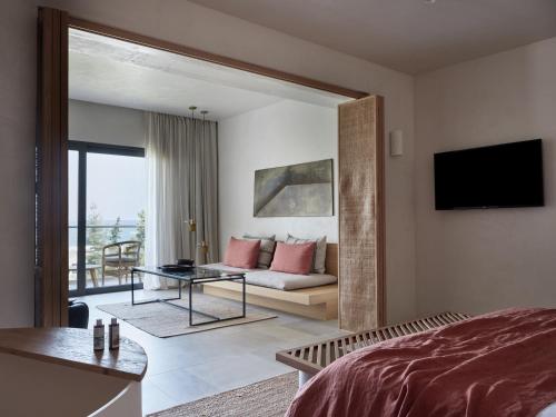 a bedroom with a bed and a living room at Port Royal Villas and Spa - Adults Only in Kolimbia