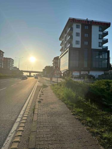 a building on the side of a road with the sunset at Plaja Yakın Konforlu Aile Yuvası in Piraziz