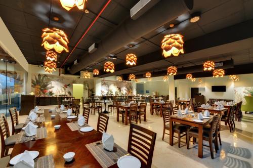 a restaurant with wooden tables and chairs and lights at The Fern Residency, Vadgaon - Talegaon, Pune in Pune