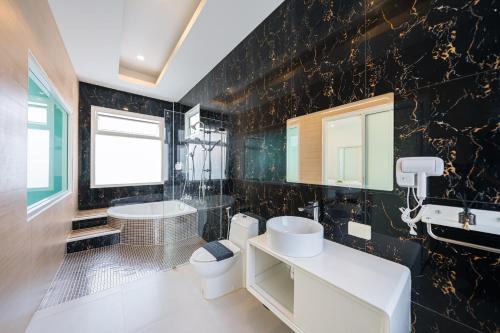 a bathroom with a sink and a toilet and a tub at Leon Pool Villa Pattaya in Ban Huai Yai