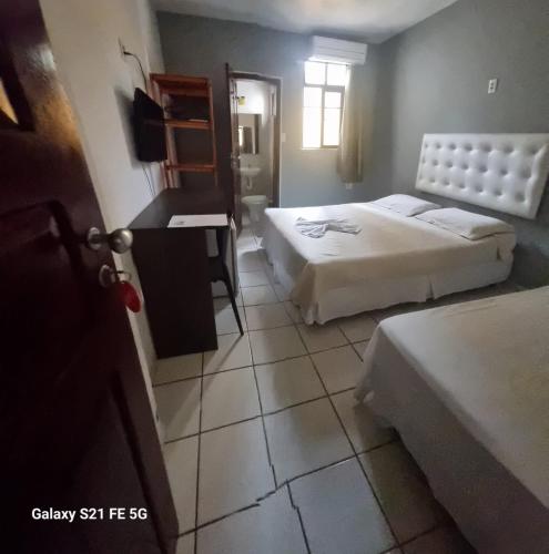 a bedroom with two beds and a desk in it at Hotel Netuno Beach in Fortaleza