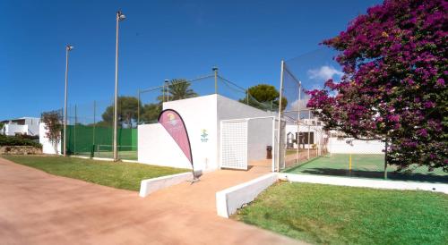 a building with a tennis court with purple flowers at Hotel Calimera Fido Gardens in Cala d´Or