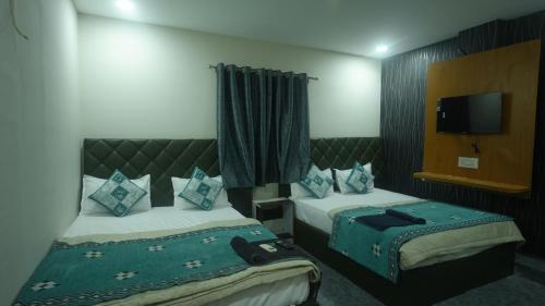 a hotel room with two beds and a flat screen tv at Hotel Mahakal Avantika Palace in Ujjain