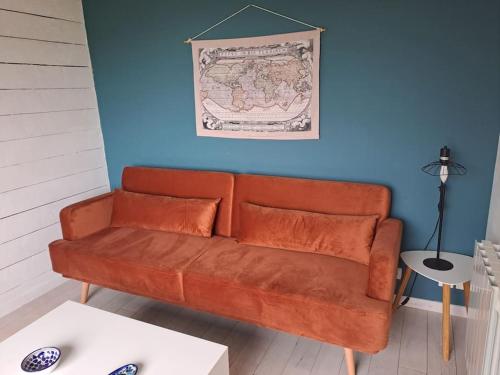 an orange couch in a room with a blue wall at Chalet en Bois Unique Séjour Inoubliable Face à la Mer in Plérin
