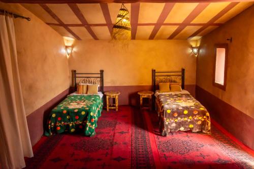a room with two beds and a red carpet at Mhamid Nomad Camp in Mhamid