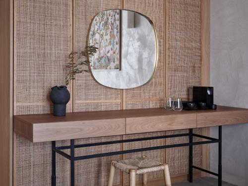 a mirror on a wall with a table and a chair at Port Royal Villas and Spa - Adults Only in Kolimbia