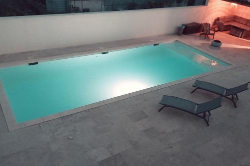 une grande piscine avec deux chaises et une table dans l'établissement Villa moderne avec piscine, à Monteux