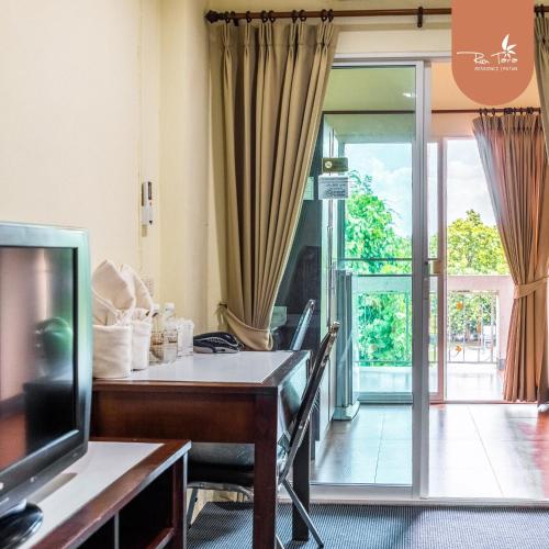 a living room with a table and a tv and a sliding glass door at rimtara residence patan in Chiang Mai