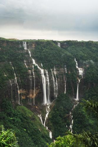 a waterfall in the middle of a mountain with trees at Polo Cherrapunjee Resort in Cherrapunji