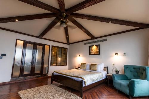 a bedroom with a bed and a blue chair at Polo Cherrapunjee Resort in Cherrapunji