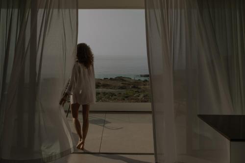 a woman in a white dress looking out of a window at Kora Nivaria Beach in Abades