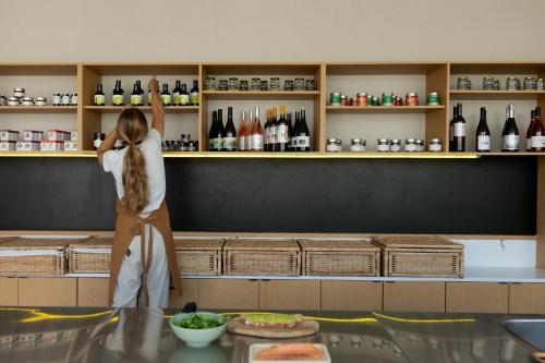 a woman is reaching up on a shelf in a restaurant at Kora Nivaria Beach in Abades