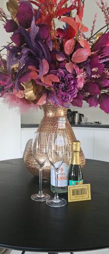 two wine glasses and a vase with a flower arrangement at Casa Roberto in Alkmaar