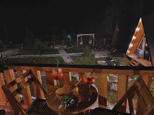 a table on a deck with two glasses of wine at Thethi Villas in Theth
