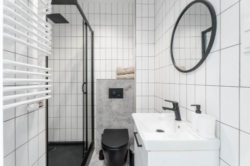 een badkamer met een wastafel, een toilet en een spiegel bij Chill Apartments Pileckiego in Warschau