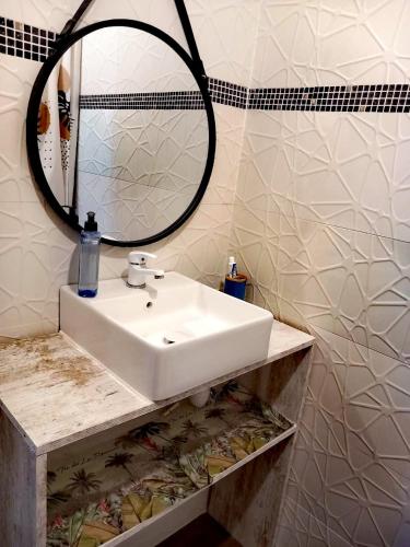 a bathroom with a white sink and a mirror at Location bord océan, Holi-Wood in Saint-Joseph