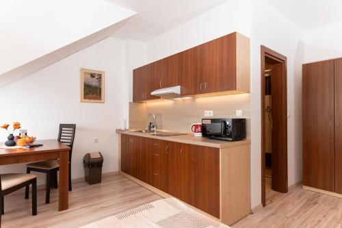 a kitchen with wooden cabinets and a table with a microwave at SISI Pension in Púchov