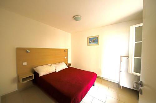 une chambre avec un lit avec une couverture rouge dans l'établissement Les Voiles Blanches, à Sari-Solenzara