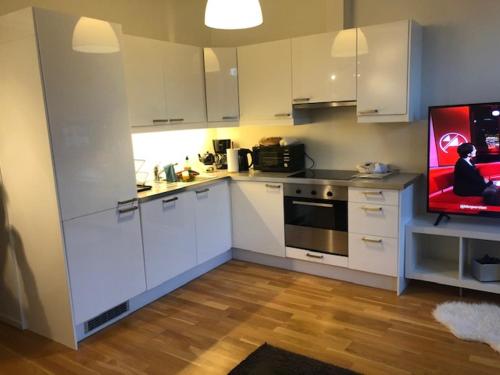 a kitchen with white cabinets and a flat screen tv at Engen 6 in Bergen