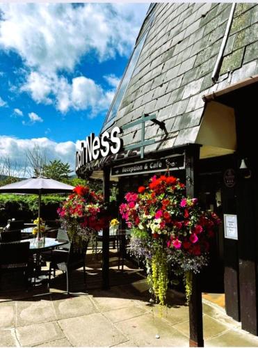 a restaurant with flowers in front of a building at Loch Ness Drumnadrochit Hotel in Drumnadrochit