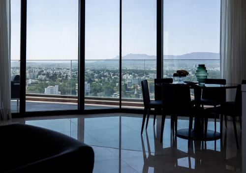 a dining table and chairs in a room with a large window at Nicosia Central Park Residences in Nicosia