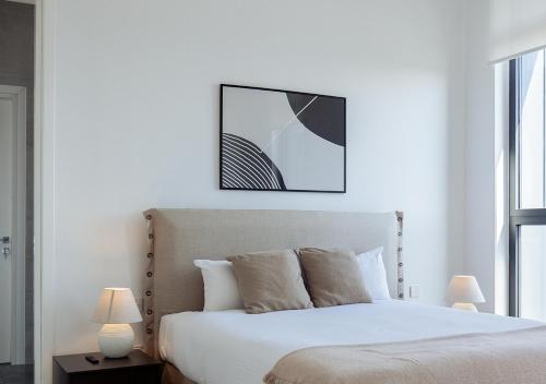 a bedroom with a white bed with a picture above it at Nicosia Central Park Residences in Nicosia