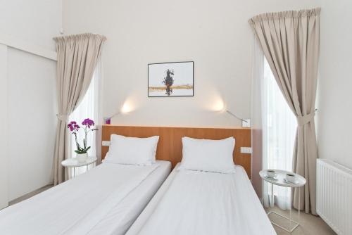 two beds in a room with white walls and curtains at Villa 21 Victus by Noclegi Renters in Sopot