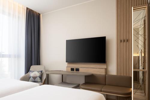 a hotel room with a bed and a tv at Courtyard by Marriott Milano Linate in Milan