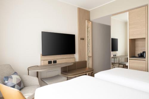 a hotel room with a bed and a television at Courtyard by Marriott Milano Linate in Milan