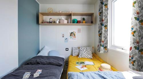 une petite chambre avec deux lits et une fenêtre dans l'établissement Mobil home 3 chambres climatisé, à Saint-Julien-en-Born