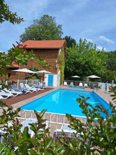 une grande piscine avec des chaises et une maison dans l'établissement Mobil home 3 chambres climatisé, à Saint-Julien-en-Born