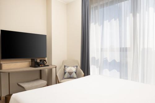 a bedroom with a bed and a tv and a chair at Courtyard by Marriott Milano Linate in Milan