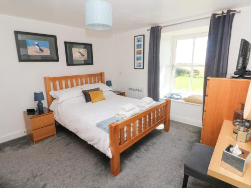 a bedroom with a wooden bed and a window at Grassholm View in Haverfordwest