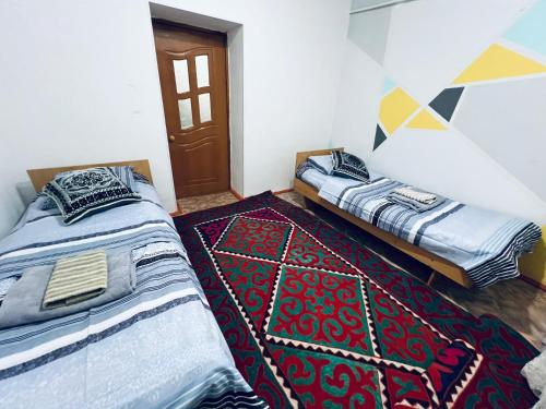 two beds sitting in a room with a rug at SIA Guest House in Naryn
