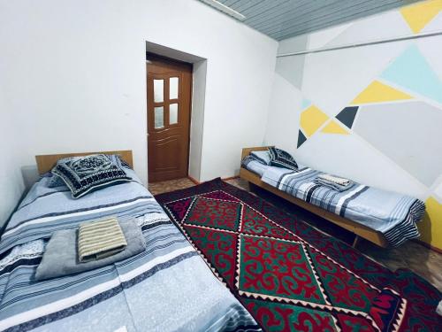 a bedroom with two beds and a rug at SIA Guest House in Naryn