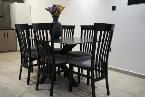 a table with four chairs and a vase with flowers at Lazuli Urban Luxury -2 bedroom with Pool in Larnaka