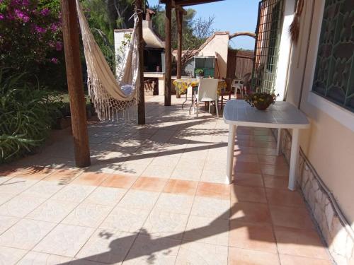 a patio with a hammock and a table and chairs at Isuedda in Marrùbiu