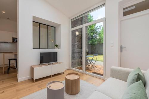 un salon avec un canapé et une télévision dans l'établissement Appartement une chambre avec jardin, proche tram, à Tourcoing