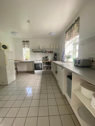a kitchen with white appliances and a white tiled floor at Guesthouse Hraunbaer in Aðaldalur