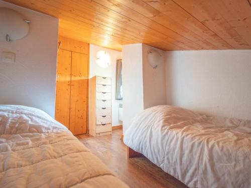 une chambre avec deux lits et un plafond en bois dans l'établissement Duplex 5 pièces avec balcon, animaux acceptés, skis aux pieds - FR-1-291-732, à Valmorel