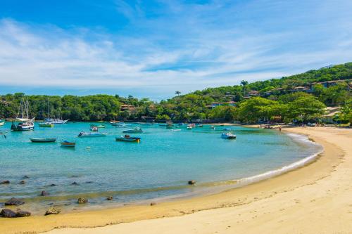 a group of boats in the water on a beach at La Chimère Buzios Essence in Búzios